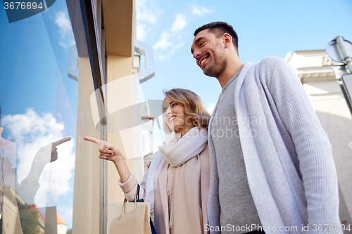 Image of happy couple with shopping bags at shop window