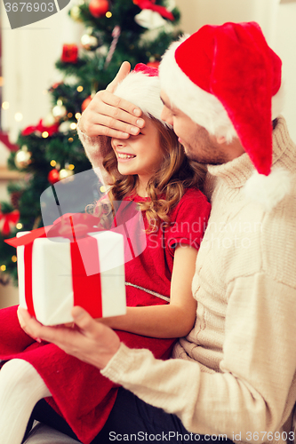 Image of smiling father surprises daughter with gift box