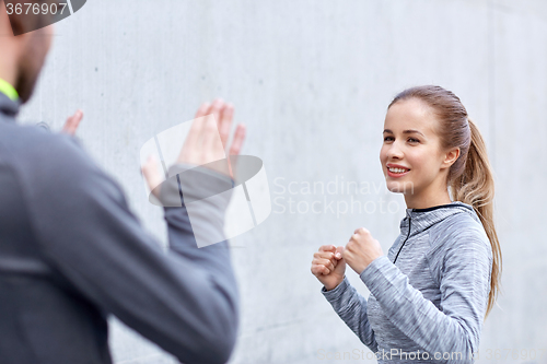 Image of happy woman with coach working out strike outdoors