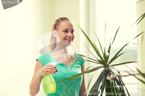 Image of happy woman in spraying houseplants at home