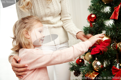 Image of happy family decorating christmas tree at home