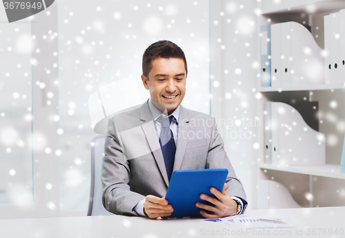 Image of smiling businessman with tablet pc in office