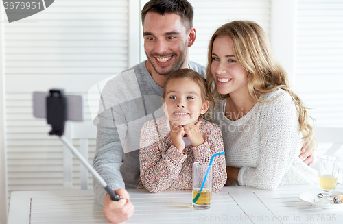 Image of happy family taking selfie at restaurant