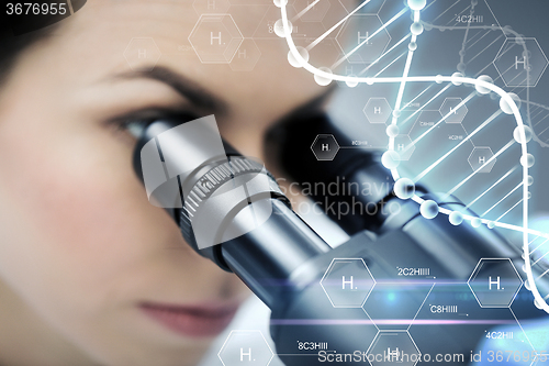 Image of close up of scientist looking to microscope in lab