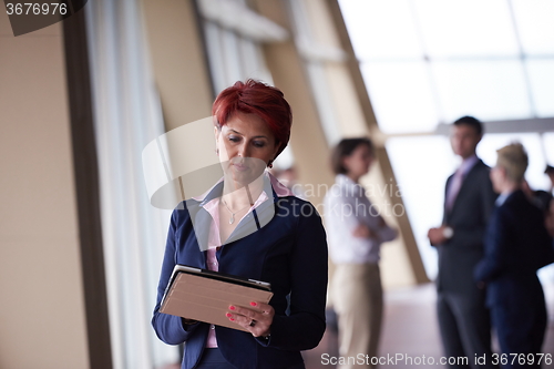 Image of business woman  at office with tablet  in front  as team leader