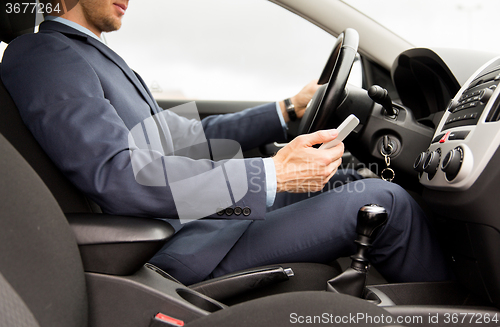 Image of close up of man with smartphone driving car