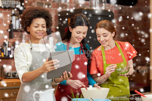 Image of happy women with tablet pc cooking in kitchen