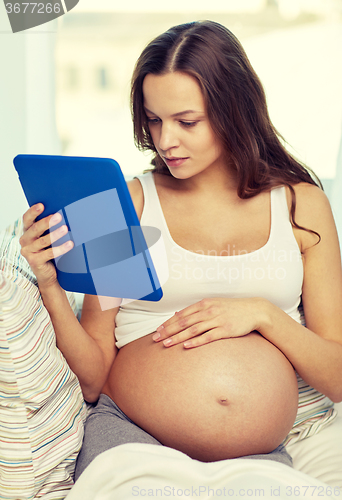Image of happy pregnant woman with tablet pc at home