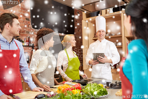 Image of happy friends with tablet pc in kitchen