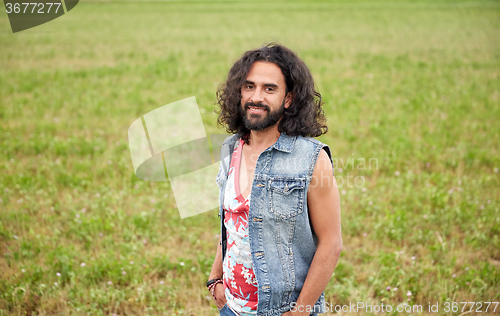 Image of smiling young hippie man on green field