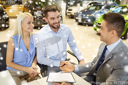 Image of happy couple with car dealer in auto show or salon