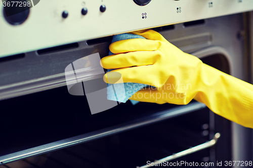 Image of close up of woman cleaning oven at home kitchen