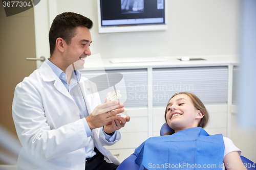 Image of happy dentist showing jaw layout to patient girl