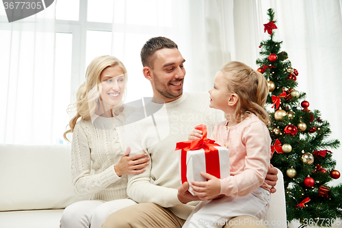 Image of happy family at home with christmas gift