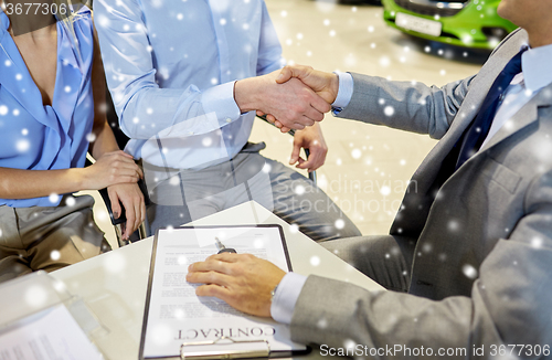 Image of handshake of customer and car dealer in auto salon