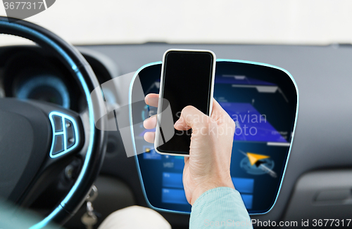 Image of close up of male hand with smartphone driving car