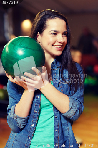 Image of happy young woman holding ball in bowling club