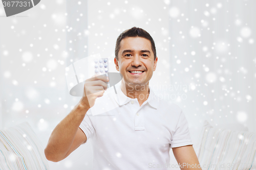 Image of happy man showing pack of pills at home