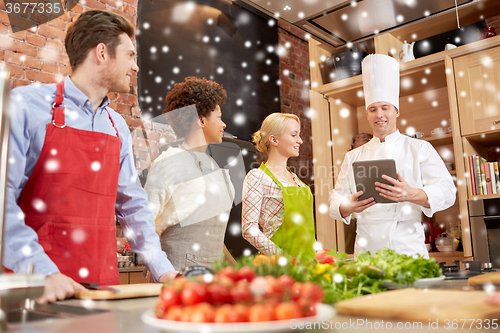 Image of happy friends with tablet pc in kitchen