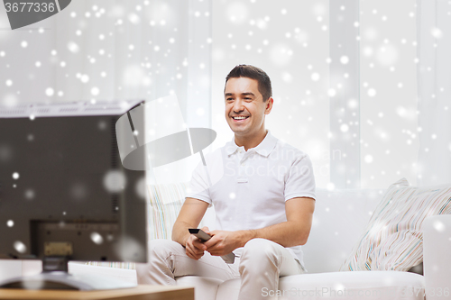 Image of smiling man with remote control watching tv