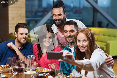 Image of friends taking selfie by smartphone at restaurant