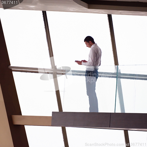 Image of young successful business man in penthouse apartment working on 