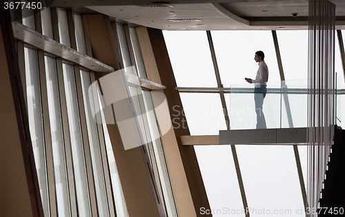 Image of young successful business man in penthouse apartment working on 