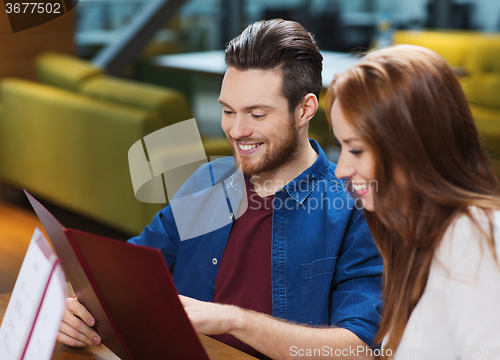 Image of smiling couple with menus at restaurant