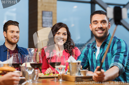 Image of friends taking selfie by smartphone at restaurant