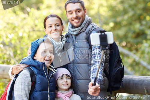 Image of happy family with smartphone selfie stick in woods