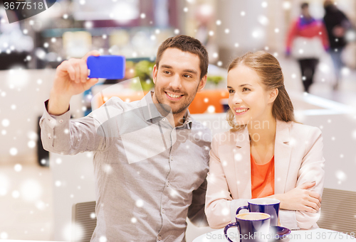 Image of happy couple with smartphone taking selfie in mall