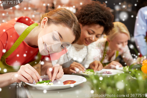 Image of happy women cooking and decorating dishes