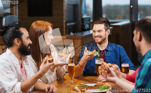 Image of friends eating pizza with beer at restaurant