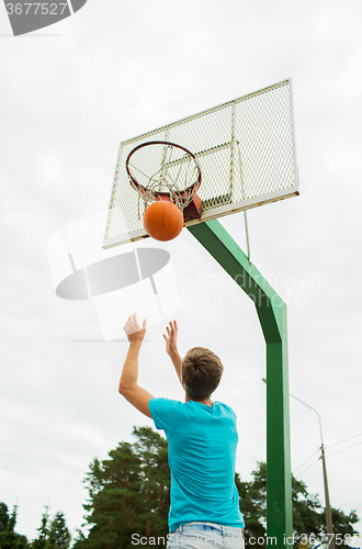 Image of young man playing basketball outdoors