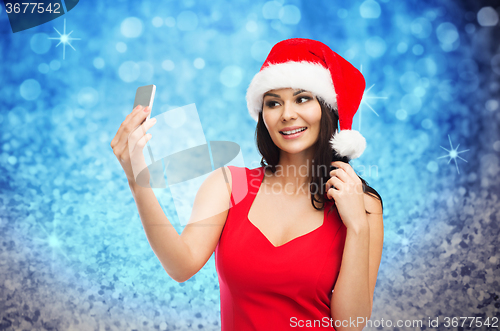 Image of woman in santa hat taking selfie by smartphone