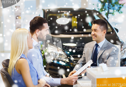 Image of happy couple with car dealer in auto show or salon