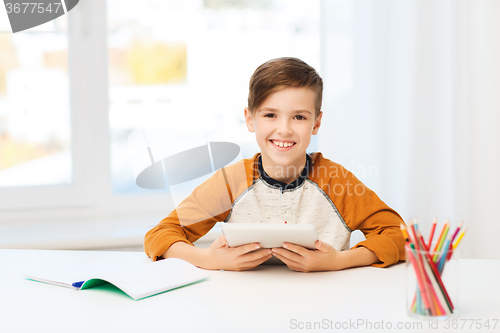 Image of smiling boy with tablet pc and notebook at home