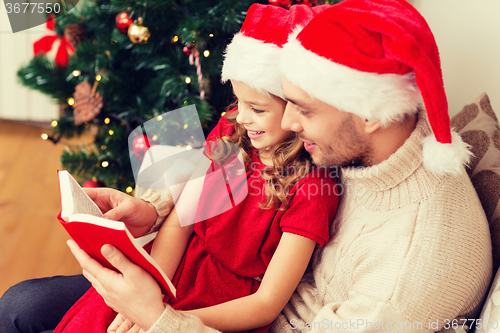 Image of smiling father and daughter reading book