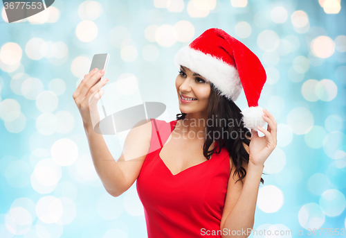 Image of woman in santa hat taking selfie by smartphone