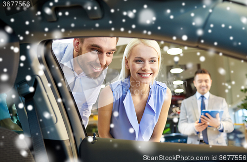 Image of happy couple with car dealer in auto show or salon