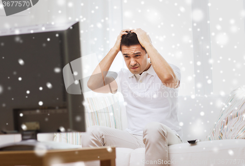 Image of disappointed man watching tv at home