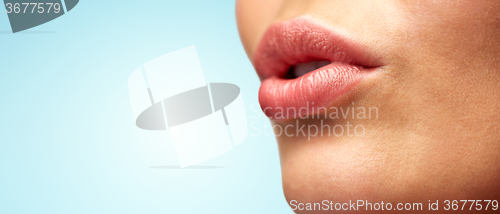 Image of close up of young woman lips over blue