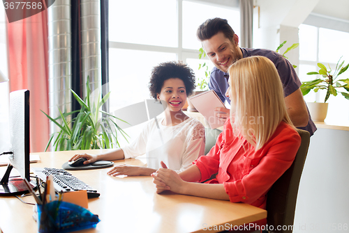 Image of happy creative team with computer in office