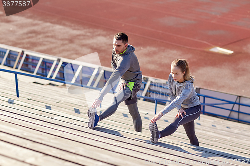 Image of couple stretching leg on stands of stadium