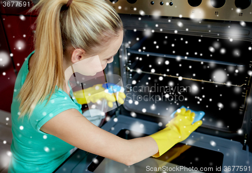 Image of happy woman cleaning cooker at home kitchen