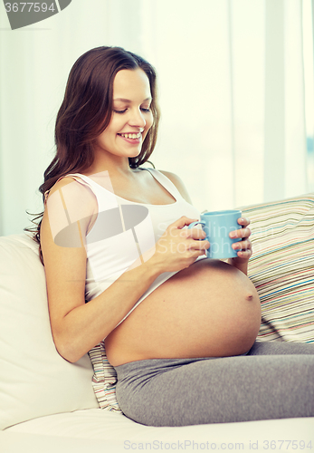 Image of happy pregnant woman with cup drinking tea at home