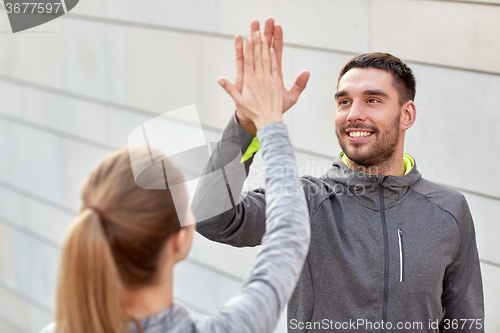 Image of happy couple giving high five outdoors