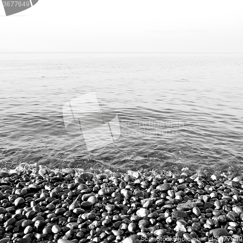 Image of stone in the coastline sunrise and light ocean white sky