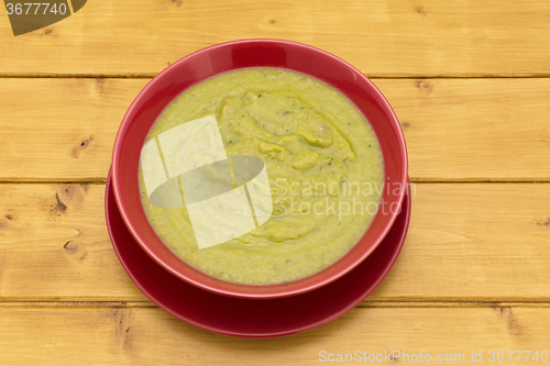 Image of Bowl of green soup in a red bowl