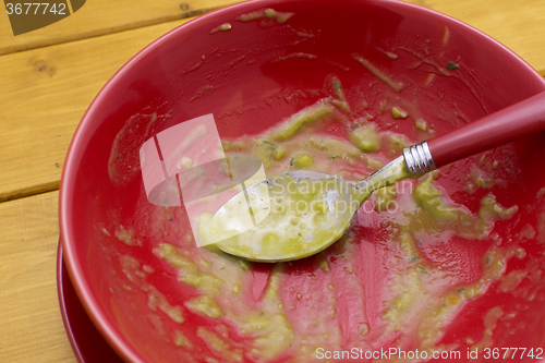 Image of Dregs of pea and ham soup in a red bowl